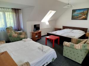 a hotel room with two beds and chairs and a tv at Penzión Malý Dvor in Štúrovo