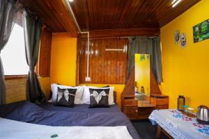 a bedroom with two beds and a yellow wall at Dixit Homestaay & Hostel in Darjeeling +9 photos