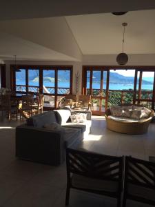 a living room with couches and a view of the ocean at Casa de Luxo em Ilhabela vista para o Mar - Condominio Yacamin- Praia do Curral in Ilhabela