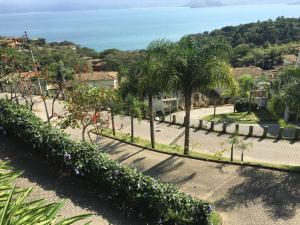 a view of a park with palm trees and the ocean at Casa de Luxo em Ilhabela vista para o Mar - Condominio Yacamin- Praia do Curral in Ilhabela