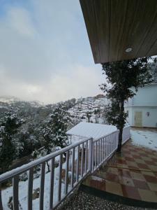 a balcony of a house with snow on the ground at frozen valley in Mukteshwar
