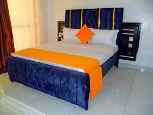a bedroom with a bed with an orange and blue headboard at Rosa Mystica Diani Bnb in Ukunda Airport +16 photos