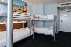 a room with three bunk beds with white sheets at Rotterdam Teleport Hostel in Rotterdam