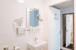 a white bathroom with a sink and a mirror at Rotterdam Teleport Hostel in Rotterdam