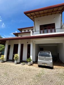 a white car parked in front of a house at Nymph Villa in Pannipitiya