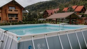 a swimming pool in front of a log house at Beauty House in Mykulychyn