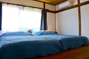 a bedroom with a bed with blue sheets and a window at パノラマスター白子-Panoramastars Shirako-星降る夜の貸切ステイ in Shirako