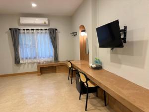 a room with a desk with a television and chairs at JanJao Resort in Nakhon Sawan