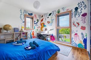 a bedroom with a blue bed with colorful wallpaper at Breizh'ome in Saint-Cast-le-Guildo +27 photos