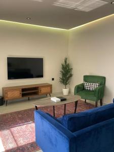 a living room with two blue chairs and a television at شقق سكنية بالربوة2 in Medina