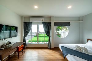 a bedroom with a bed and a desk and a window at Sinai Rimtalay Hotel in Ban Nong Sanom