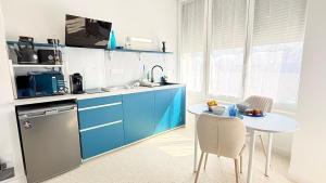 a kitchen with blue cabinets and a table with chairs at Studio Ty Lys lumineux, climatisé, balcon, parking gratuit Classé 3 étoiles in Blois