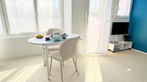 a white table and chairs in a room with a tv at Studio Ty Lys lumineux, climatisé, balcon, parking gratuit Classé 3 étoiles in Blois +11 photos