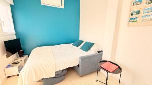 a bedroom with a bed with a blue wall at Studio Ty Lys lumineux, climatisé, balcon, parking gratuit Classé 3 étoiles in Blois
