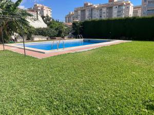 a swimming pool in a yard with grass and buildings at Villa Dopimar in Rincón de la Victoria