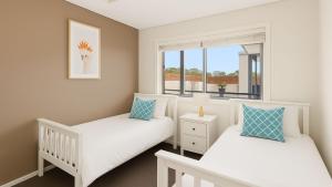 two beds in a room with a window at Solaris in Fingal Bay