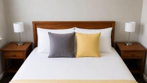 a bed with three pillows and two lamps on it at Solaris in Fingal Bay +9 photos
