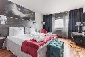 a hotel room with a large bed with a desk at Quality Hotel Sundsvall in Sundsvall