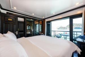 a bedroom with a large white bed and a balcony at Cruise Lan Ha Bay 2 Day 1 Night pick-up from Cat Ba Central in Cat Ba