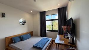 a bedroom with a bed with blue pillows and a window at Nắng Hotel in Cẩm Mỹ