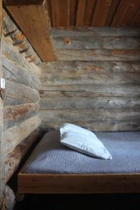 a bed in a cabin with a wooden wall at River Cabin Urpo in Inari