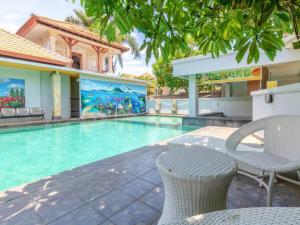 a swimming pool with a table and chairs next to a building at Guntur Hotel Bali in Ketewel