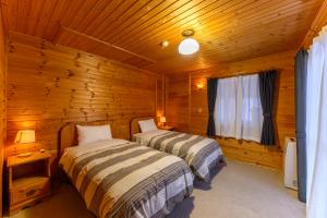 ein Schlafzimmer mit zwei Betten in einer Blockhütte in der Unterkunft Madarao Vacances Village in Iiyama