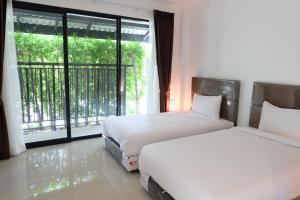 a bedroom with two beds and a large window at me2 Singhamuntra Resort Kamphaengsaen in Kamphaeng Saen