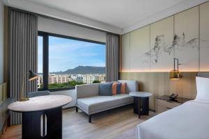 a hotel room with a bed and a couch and a window at Courtyard By Marriott Tirupati in Tirupati