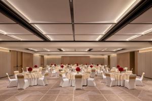 a banquet hall with white tables and chairs and red roses at Courtyard By Marriott Tirupati in Tirupati +72 photos