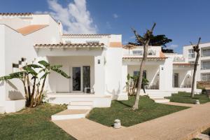 a white house with a palm tree in front of it at Minura Sur Menorca in Punta Prima