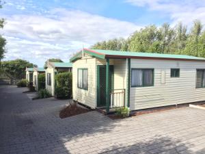 Inverloch Cabins & Apartments في إينفيرلوك: صف من البيوت المتنقلة تقف في موقف للسيارات