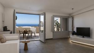a living room with a couch and a television and a table at Terracotta Sunset Suites in Oia
