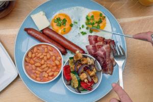 a blue plate of breakfast food with sausage beans and eggs at So Stay Bed & Breakfast - Self Check-in in Gdańsk