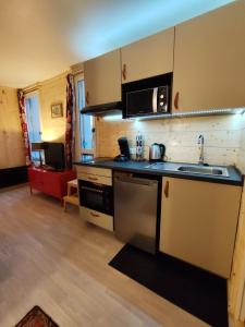 a small kitchen with a sink and a microwave at La Tanière in Ustou