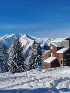 a building in the snow with mountains in the background at La Tanière in Ustou