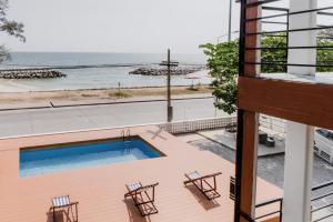 a balcony with a swimming pool and chairs and the ocean at Sinai Rimtalay Hotel in Ban Nong Sanom