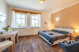 a bedroom with a bed and a desk and windows at Pension Elbrs in Mariánské Lázně