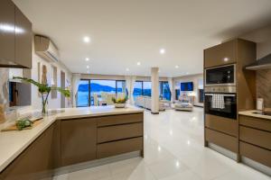 a large kitchen with brown cabinets and a living room at Oceans Eleven Villa Samui - Oceanfront, Private Pool, Perfect for families and friends in Bangrak Beach