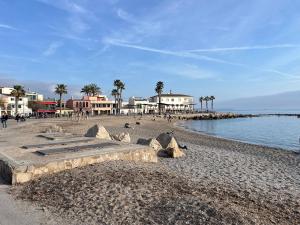 a beach with buildings and palm trees and the water at BluehousePortixol Mallorca in Palma de Mallorca