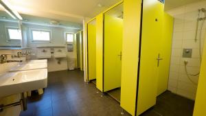 a bathroom with two sinks and yellow dividers at Brienz Youth Hostel in Brienz +29 photos