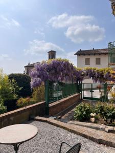 a garden with a table and purple flowers on a fence at An tij slè - Nel cuore del borgo in Guarene +30 photos
