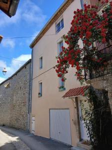 a building with red flowers on the side of it at La maisonnette in Saint-Georges-de-Luzençon