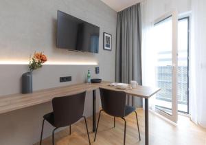 a dining room with a table and chairs and a television at Brera Serviced Apartments Singen in Singen