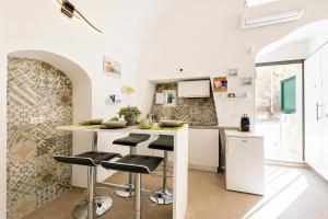 a white kitchen with a counter and stools at Venti Nodi in Vieste