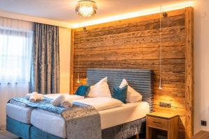 a bedroom with a large bed with a wooden wall at Das Thiers in Thiersee