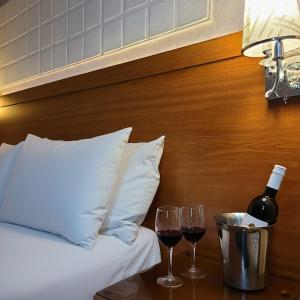 a bed with two glasses of wine on a table at C Fun Addis Hotel in Addis Ababa