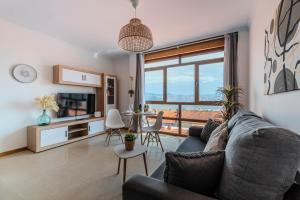 a living room with a couch and a tv and a table at El Balcon de Moaña in Moaña