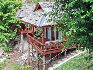 a small house with a balcony in a forest at Banua Guesthouse in Pulau Malenge