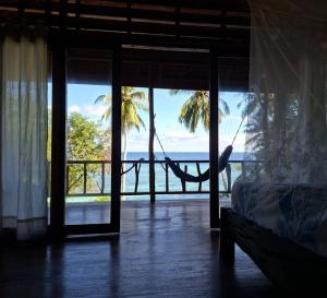 a hammock in a room with a view of the ocean at Banua Guesthouse in Pulau Malenge